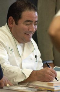 An image of Emeril Lagasse, chef, signing books 