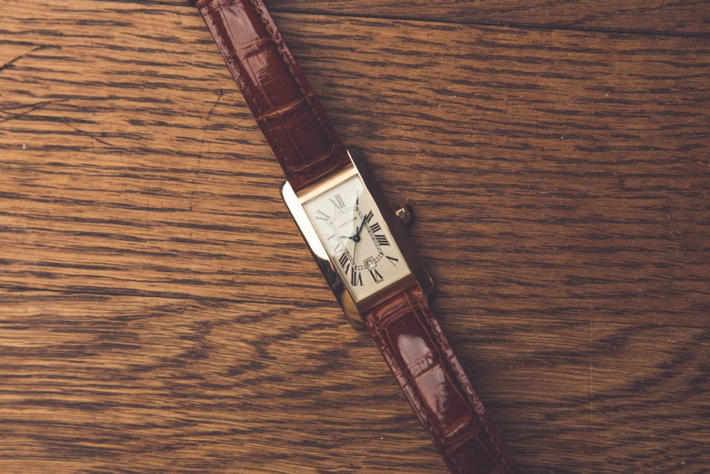 a cartier tank on laying on a wood table 